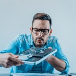 Mann repariert und reinigt Notebook