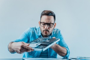 Mann repariert und reinigt Notebook